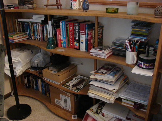 Bookshelf made my Larry Lynam.  Books, DVDs, external drive, cameras, small purple vase from Malta (C & C) and 2 little pott